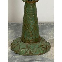 a green vase sitting on top of a cement floor