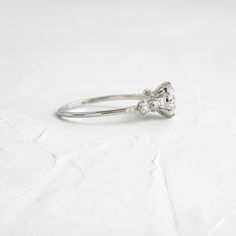 a white gold ring with two diamonds on it's sides and a bow at the top