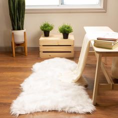 a white rug sitting on top of a hard wood floor next to a table and potted plants