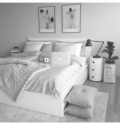 black and white photograph of a bedroom with bed, laptop and pillows