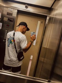 a man standing in front of an elevator holding a cell phone