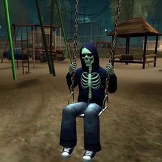 a skeleton sitting on a swing in a park