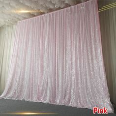 a pink wedding backdrop with sequins hanging from it's ceiling in the middle of a room