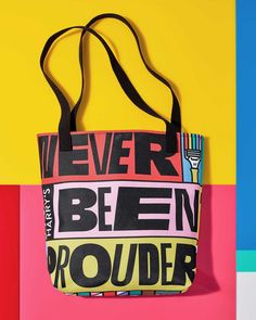 a black and white tote bag on top of a multicolored background with the words never been prouder