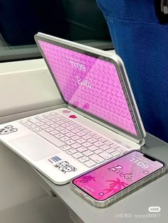 an open laptop computer sitting on top of a white desk next to a cell phone