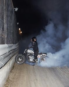 a man riding on the back of a motorcycle down a dirt road