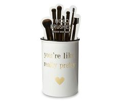 a white cup filled with makeup brushes on top of a table