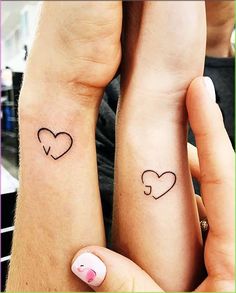 two people with matching tattoos on their arms holding each other's hands and looking at the camera