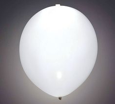 a large white balloon floating in the air on a gray background with no people around it