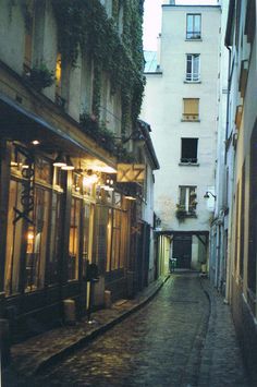 an alley way with buildings and lights on either side