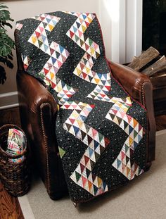 a chair with a quilt on it in front of a fireplace