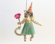 a cat ornament hanging from a string with a flower in it's mouth