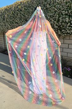 a woman wearing a rainbow colored dress with flowers on it