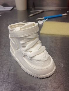 a pair of white shoes sitting on top of a table next to a cup and brush