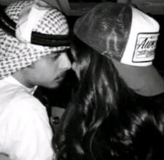 a man and woman kissing each other while wearing hats