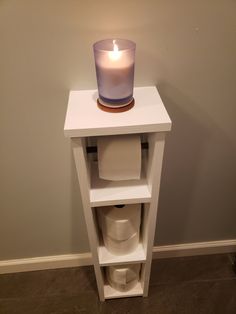 a white shelf with a lit candle on top