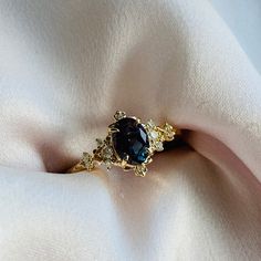 a gold ring with a blue stone on it's side sitting on a white cloth