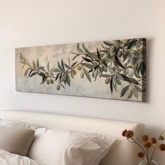 a painting hanging above a bed with white sheets and pillows on it's headboard