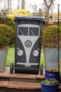 a black and white vw bus sitting next to some potted plants