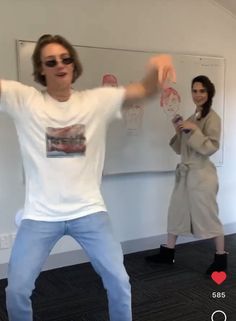 two people standing in front of a whiteboard while one person holds his hands up