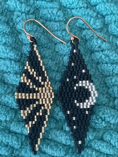 two black and white beaded earrings sitting on top of a blue blanket next to each other