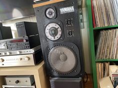 there is a large speaker on top of a shelf in the room next to other audio equipment