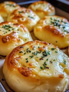 some bread rolls with cheese and herbs on them in a baking pan, ready to be baked