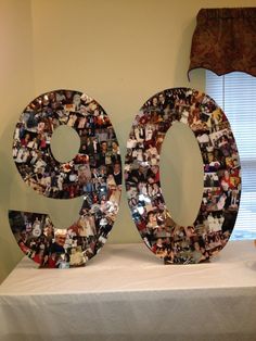 a table topped with a large number covered in lots of photos next to a window