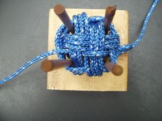 an object made out of yarn and wooden pegs on top of a wood block