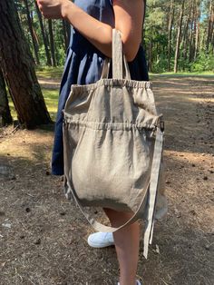 a person holding a bag in their hand while standing on the ground near some trees