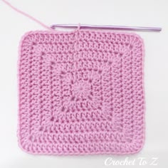 a pink crochet square with a knitting needle