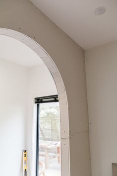 an arched window is being installed in the corner of a room that has been painted white