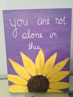 a purple sign with a yellow flower on it that says, you are not alone in this