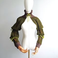 a mannequin wearing a crocheted sweater and holding her hands out to the side