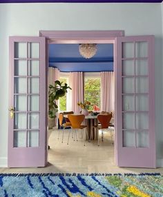 an open door leading to a dining room with purple walls and doors on either side