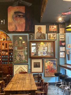 an empty restaurant with many pictures on the wall and wooden tables in front of them