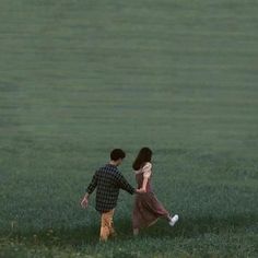 two people walking through a field holding hands