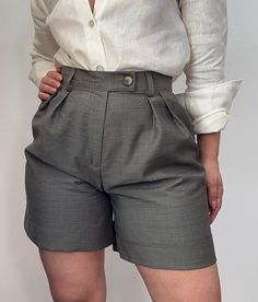 These office shorts are a sophisticated blend of luxury and comfort, crafted from natural fabrics such as silk or wool.  The high-waisted design features sharp pleats for a tailored look, while the luxurious materials add a touch of elegance. These versatile shorts are perfect for creating polished, professional outfits or chic casual ensembles. **Styling Ideas 1. **Classic Office Look Pair these shorts with a crisp white button-down shirt (as shown) and add a pair of loafers or block heels. Fin Classic Office, Longline Coat, Shorts High Waisted, Fitted Turtleneck, White Button Down Shirt, Opaque Tights, Shorts Womens, Pleated Pants, Professional Outfits