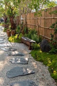 a gravel path in the middle of a garden with trees and plants on either side