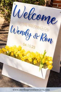 a welcome sign with yellow flowers in it