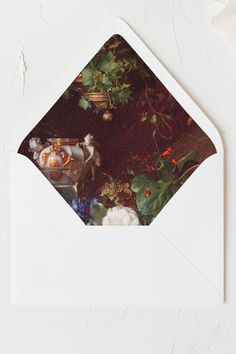 an open envelope with a photograph of flowers and fruit on the table in front of it