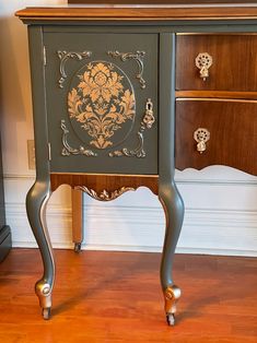 an ornately painted chest of drawers in a room with wood flooring and white walls