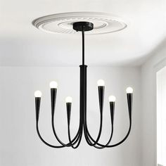 a black chandelier with five lights hanging from the ceiling in a white room