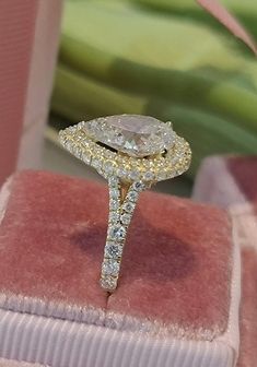 a diamond ring sitting on top of a pink velvet box