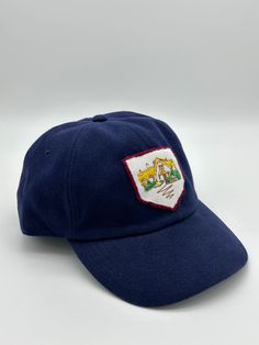 Dark blue baseball cap featuring an embroidered patch. Cap and patch are both vintage. Cap is unstructured and adjustable in size. Any idiosyncrasies, such as signs of wear or mending, are the result of the nature of the material’s long and rich history and should not be considered flaws or damage. Outdoor Patches Baseball Cap, Blue Hat With Logo Patch And Curved Brim, Blue Curved Brim Hat With Logo Patch, Navy Six-panel Baseball Cap With Logo Patch, Navy Baseball Cap With Logo Patch And Curved Bill, Vintage Blue Dad Hat, Blue Cap With Embroidered Patch, Navy Baseball Cap With Logo Patch, Blue 5-panel Baseball Cap With Logo Patch