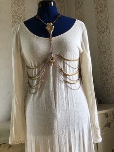 a white dress with gold chains attached to it