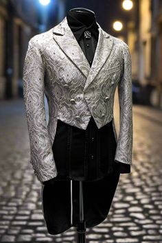 An grand gentleman's tailcoat from the days of Napoleon. A formal jacket with tails made in rich silver brocade. The jacket is cut short in front with extra long pleated tails in back. Decorated on the front with six vintage style metal lion buttons with smaller matching buttons at each cuff. This jacket is lined in sleek black satin with one left side breast pocket on the outside and one inside pocket on the right side. Comes in sizes Small-3X. So fine! Measurements: Small - Chest 40" Waist 30- Elegant Fitted Tuxedo For Costume, Elegant Long Sleeve Costume Suit, Elegant Fitted Blazer For Costume, Elegant Brocade Outerwear For Formal Occasions, Elegant Brocade Tuxedo For Wedding, Elegant Fitted Suits For Costume, Formal Fitted Silver Outerwear, Elegant Fitted Silver Suit, Elegant Formal Brocade Outerwear