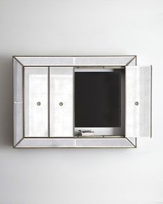 a mirror mounted on the wall with a television in it's center section and doors open