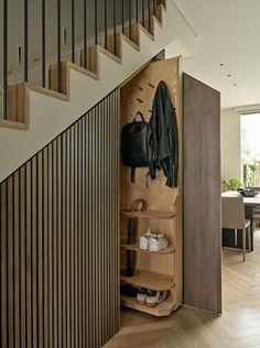 an open closet in the middle of a wooden flooring area with stairs leading up to it