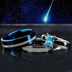 two wedding rings with an aqua blue diamond in the center and a black band around them